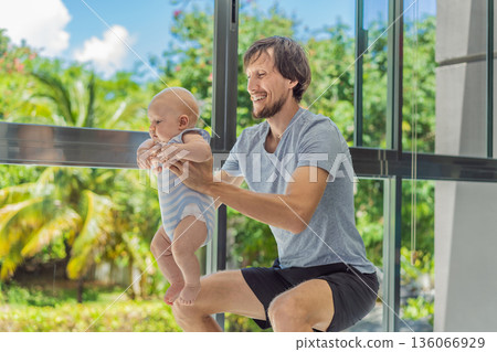 Father exercising with his small baby at home, active parenting and healthy lifestyle. Strong family bond, early physical development, modern fatherhood, fitness with children concept. 136066929