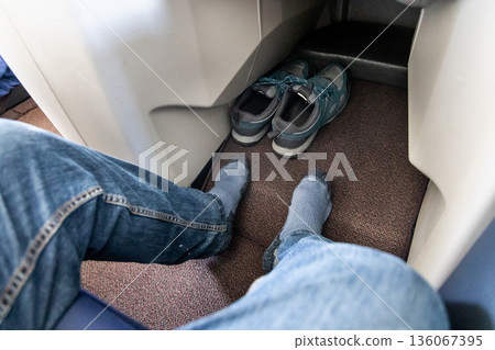Inflight business class passenger with ample leg room took off shoes during flight for comfort travel Inflight business class passenger with ample leg room took off shoes during flight for comfort travel 136067395