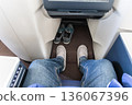 Inflight business class passenger with ample leg room replaces shoes with disposable slippers during flight for comfort travel 136067396