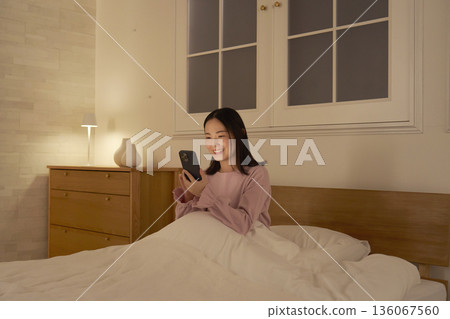 一個在床上使用智能手機的女人 136067560