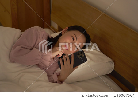 一名女子在床上使用智慧型手機 136067564