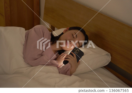 一名女子在床上玩智慧型手機時睡著了 136067565