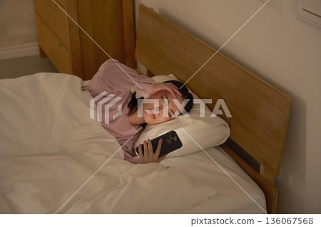 Woman looking at smartphone in futon 136067568