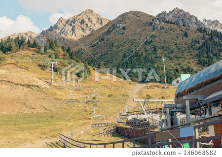 scenic view of mountains with a cable car station. The landscape features green hills and a clear blue sky, ideal for a vacation getaway. scenic view of mountains with a cable car station. The landscape features green hills and a clear blue sky, ideal for a vacation getaway. 136068582