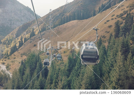 cable car with solar panel travels up a mountain slope. The landscape features rocky terrain and trees. soft, indicating a pleasant vacation atmosphere cable car with solar panel travels up a mountain slope. The landscape features rocky terrain and trees. soft, indicating a pleasant vacation atmosphere 136068609