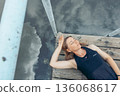 woman relaxing on dock surrounded by still water, green nature, concept of self care, weekend getaway, calm, top view 136068617