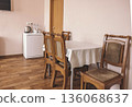 A cozy hotel dining area with a wooden table and four chairs. A small refrigerator and kettle are visible. The walls are painted in soft colors, creating a welcoming atmosphere. 136068637