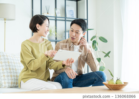 A middle-aged couple using a tablet device in the living room A middle-aged couple using a tablet device in the living room 136068866