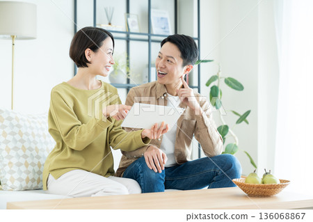 A middle-aged couple using a tablet device in the living room A middle-aged couple using a tablet device in the living room 136068867