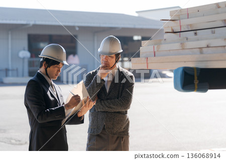 Men in suits looking at lumber at a lumberyard 136068914