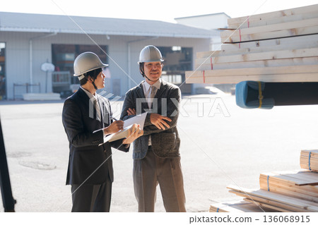 Men in suits looking at lumber at a lumberyard 136068915
