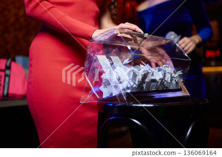 Guests select raffle tickets eagerly, People reach into box to pick lucky raffle slip, Participants eagerly reach into transparent container for their chance to win prize 136069164