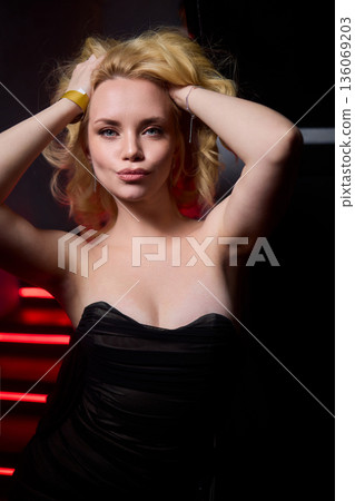 Elegant night scene, Sophisticated female model exuding confidence during evening event, Fashion forward woman highlighted by striking red lighting at glamorous social gathering Elegant night scene, Sophisticated female model exuding confidence during evening event, Fashion forward woman highlighted by striking red lighting at glamorous social gathering 136069203