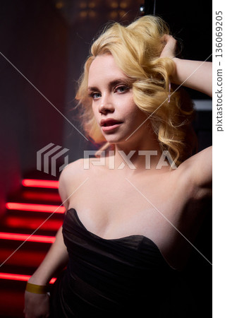 Elegant night scene, Sophisticated female model exuding confidence during evening event, Fashion forward woman highlighted by striking red lighting at glamorous social gathering Elegant night scene, Sophisticated female model exuding confidence during evening event, Fashion forward woman highlighted by striking red lighting at glamorous social gathering 136069205