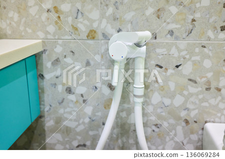 Modern ceramic fixture with flexible hose, Close view of hygienic bathroom cleaning equipment, Contemporary sanitary fixture featuring spray connected to wall valve 136069284