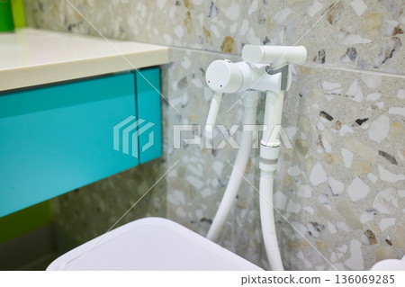 Modern ceramic fixture with flexible hose, Close view of hygienic bathroom cleaning equipment, Contemporary sanitary fixture featuring spray connected to wall valve 136069285