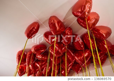 Red balloons set mood, Bright red heart shaped balloons enhance celebration ambiance, Colorful helium balloons cast romantic glow during festive events and parties 136069570