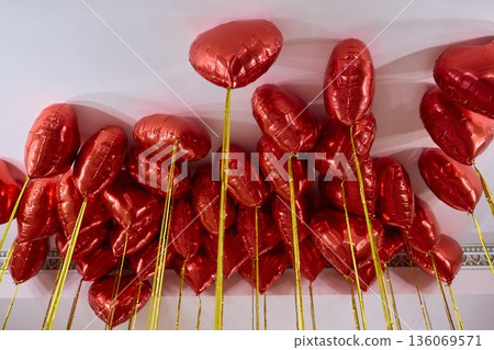 Red balloons set mood, Bright red heart shaped balloons enhance celebration ambiance, Colorful helium balloons cast romantic glow during festive events and parties 136069571