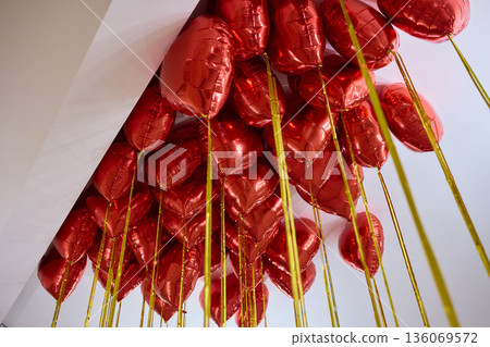 Red balloons set mood, Bright red heart shaped balloons enhance celebration ambiance, Colorful helium balloons cast romantic glow during festive events and parties Red balloons set mood, Bright red heart shaped balloons enhance celebration ambiance, Colorful helium balloons cast romantic glow during festive events and parties 136069572