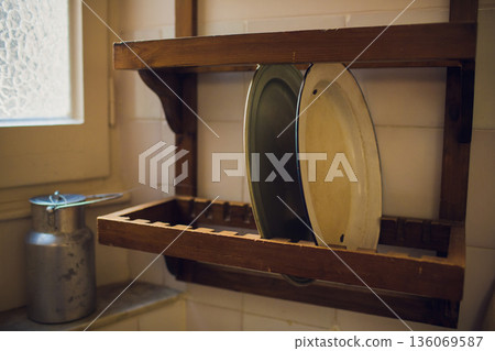 Cozy vintage breakfast scenario. Sunlit rural kitchen displaying handmade ceramics and antiques. Warm rustic kitchen scene with vintage dishes and old-fashioned accessories 136069587