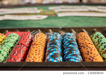 Multicolored poker chips laid out on felt table with blurred casino background, Vibrant poker chips organized on felt with shallow focus and anticipation filled casino setting Multicolored poker chips laid out on felt table with blurred casino background, Vibrant poker chips organized on felt with shallow focus and anticipation filled casino setting 136069644