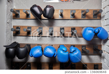 Boxing gear organized, Prepared equipment displayed neatly, Gloves systematically arranged in gym, Gym storage features lined boxing gloves in orderly environment 136069648