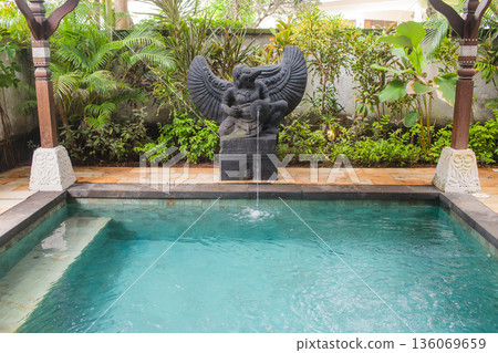 Tranquil turquoise sanctuary featuring lush plants and water features, Intimate garden space showcasing decorative fountain amid flourishing greenery and calming water elements 136069659