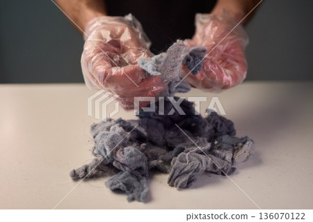 Detailed scene showing lint and cleaning, Warm indoor shot of hands clearing dryer lint, Closeup capturing hands inspecting fluffy lint fibers from machine filter Detailed scene showing lint and cleaning, Warm indoor shot of hands clearing dryer lint, Closeup capturing hands inspecting fluffy lint fibers from machine filter 136070122