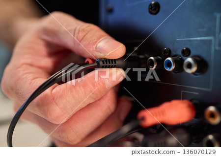 Setting up audio connection professionally, Attaching sound cable to subwoofer in studio, Closeup of hands securing audio cable into subwoofer in recording studio setting 136070129