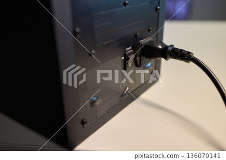 Checking subwoofer connection details, Close view of fingertip near cable connection, Detailed inspection of subwoofer power port with ambient lighting and focus on fingertip 136070141