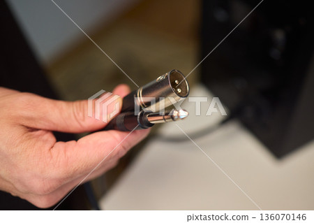 Setting up audio connection professionally, Attaching sound cable to subwoofer in studio, Closeup of hands securing audio cable into subwoofer in recording studio setting Setting up audio connection professionally, Attaching sound cable to subwoofer in studio, Closeup of hands securing audio cable into subwoofer in recording studio setting 136070146