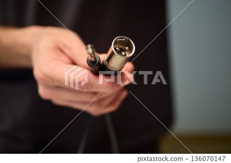 Setting up audio connection professionally, Attaching sound cable to subwoofer in studio, Closeup of hands securing audio cable into subwoofer in recording studio setting 136070147