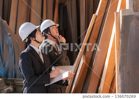 Men in suits looking at lumber at a lumberyard 136070269