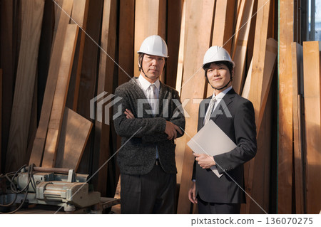 穿著西裝的男人們在木材工廠挑選木材。 穿著西裝的男人們在木材工廠挑選木材。 136070275