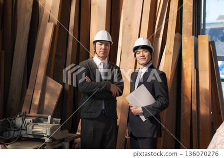 Men in suits looking at lumber at a lumberyard 136070276