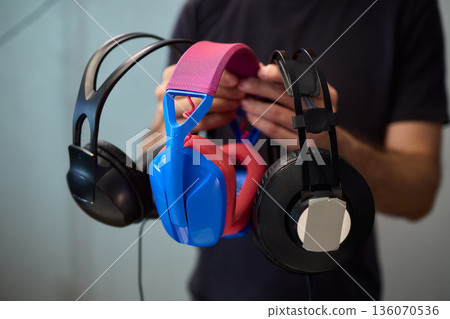 Happy guy with headphones, Casual man showcases vibrant headphones, Casually dressed man with curly hair showcases playful headphones during informal indoor photography session Happy guy with headphones, Casual man showcases vibrant headphones, Casually dressed man with curly hair showcases playful headphones during informal indoor photography session 136070536
