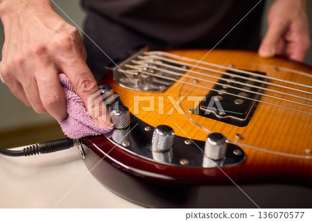 Closeup of guitar care and preparation process with studio lighting, Careful guitar body polishing and setup under professional studio lights before stage performance 136070577