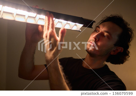 Professional adjusting illumination while managing studio supports meticulously, Creative technician balancing lights and equipment to achieve cinematic teal ambiance 136070599