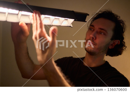 Professional adjusting illumination while managing studio supports meticulously, Creative technician balancing lights and equipment to achieve cinematic teal ambiance 136070600