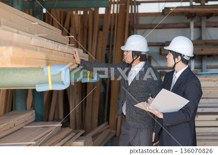 Men in suits looking at lumber at a lumberyard 136070826