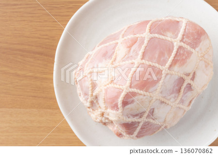 Close-up of pork leg ham wrapped in string on a plate 136070862