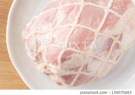 Close-up of pork leg ham wrapped in string on a plate 136070865