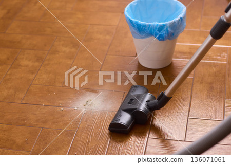 Hardwood floor vacuum head gliding across polished parquet, closeup of nozzle brushing wood grain, warm lighting, quiet household cleaning, gentle maintenance mood Hardwood floor vacuum head gliding across polished parquet, closeup of nozzle brushing wood grain, warm lighting, quiet household cleaning, gentle maintenance mood 136071061