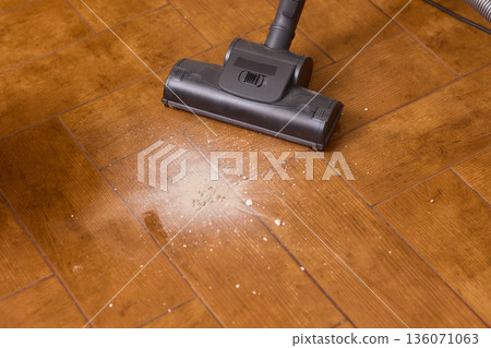 Hardwood floor vacuum head gliding across polished parquet, closeup of nozzle brushing wood grain, warm lighting, quiet household cleaning, gentle maintenance mood 136071063