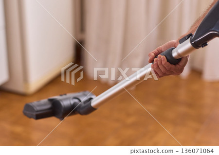 Hardwood floor vacuum head gliding across polished parquet, closeup of nozzle brushing wood grain, warm lighting, quiet household cleaning, gentle maintenance mood 136071064