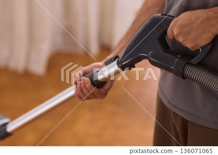 Hardwood floor vacuum head gliding across polished parquet, closeup of nozzle brushing wood grain, warm lighting, quiet household cleaning, gentle maintenance mood 136071065