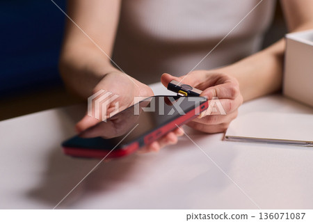 Lavalier attachment to phone for rapid interview recordings. Onsite interview preparation involving portable microphone and quick assembly tools in natural lighting conditions 136071087