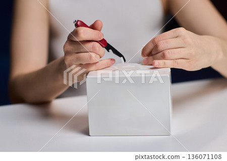 Closeup of hands verifying box. Hands carefully opening and examining container edges. Professional hands meticulously inspecting and verifying condition of sealed white box Closeup of hands verifying box. Hands carefully opening and examining container edges. Professional hands meticulously inspecting and verifying condition of sealed white box 136071108