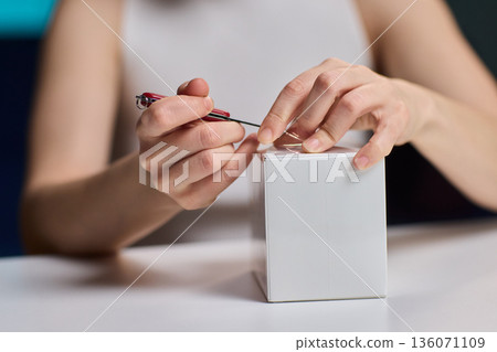 Closeup of hands verifying box. Hands carefully opening and examining container edges. Professional hands meticulously inspecting and verifying condition of sealed white box Closeup of hands verifying box. Hands carefully opening and examining container edges. Professional hands meticulously inspecting and verifying condition of sealed white box 136071109