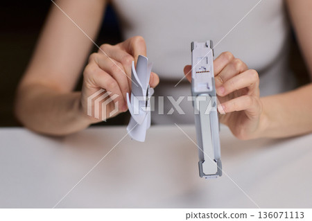 Detailed scene with technician disassembling small desktop fan carefully. Precise hands removing cover of desk fan during technical inspection with focused lighting 136071113